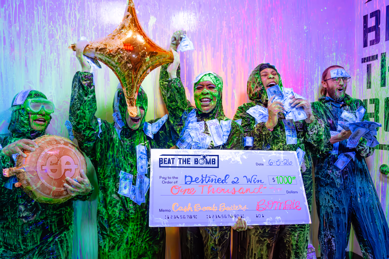 Slime-covered team celebrating a Cash Bomb win with a giant $1,000 cheque